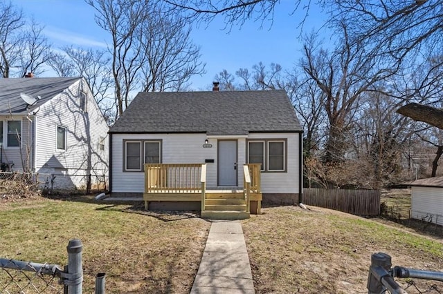 bungalow with fence, roof with shingles, a wooden deck, a chimney, and a front lawn