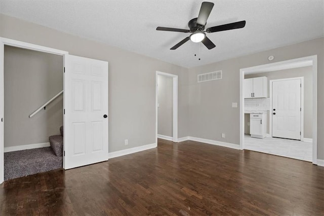 unfurnished living room featuring visible vents, wood finished floors, baseboards, ceiling fan, and stairs