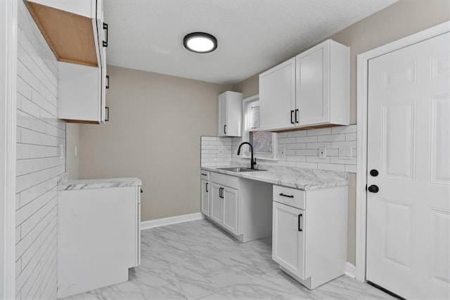 3403 Norton Ave, Kansas City, MO 64128 - kitchen featuring baseboards, a sink, white cabinetry, marble finish floor, and backsplash