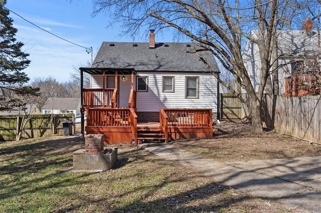 3403 Norton Ave, Kansas City, MO 64128 - back of house with a wooden deck, a fenced backyard, roof with shingles, and a chimney