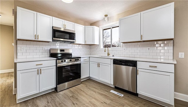 kitchen featuring stainless steel appliances, light countertops, light wood-style floors, and a sink