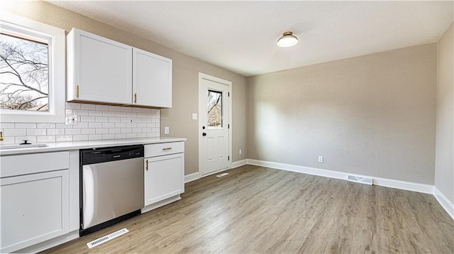 kitchen with visible vents, light wood finished floors, decorative backsplash, light countertops, and dishwasher