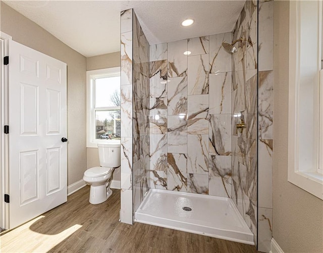 full bath with toilet, wood finished floors, baseboards, and a marble finish shower