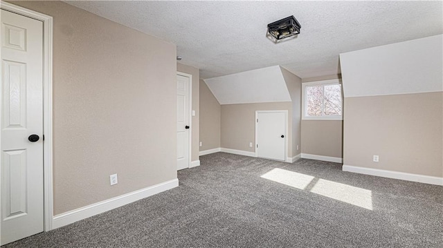 additional living space with baseboards, a textured ceiling, carpet, and vaulted ceiling