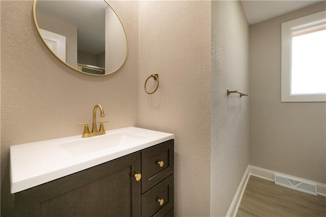 bathroom featuring vanity, wood finished floors, visible vents, and baseboards