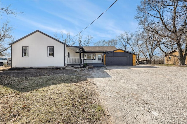 single story home with a porch, a garage, and dirt driveway