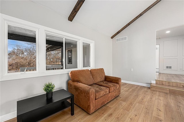 living area featuring lofted ceiling with beams, visible vents, baseboards, and light wood-style flooring