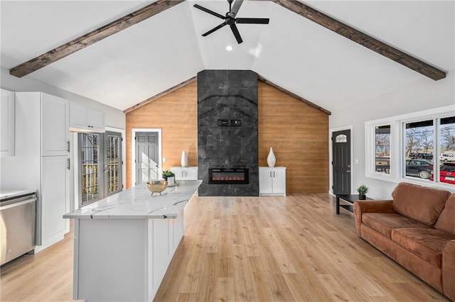 living room featuring wooden walls, vaulted ceiling with beams, ceiling fan, light wood-type flooring, and a fireplace