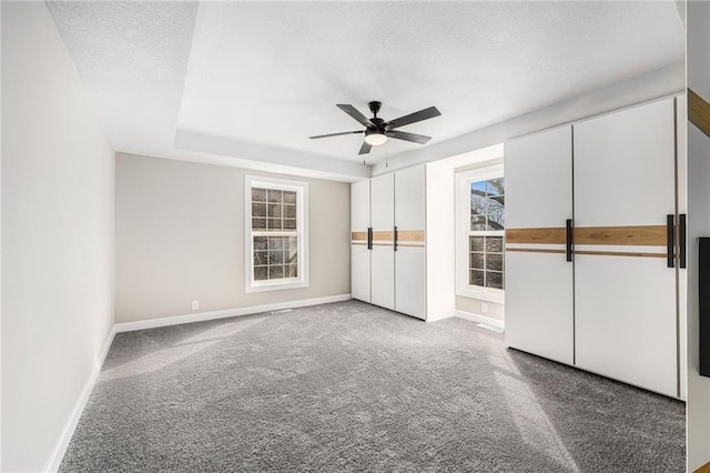 unfurnished bedroom with a textured ceiling, a ceiling fan, baseboards, and carpet floors