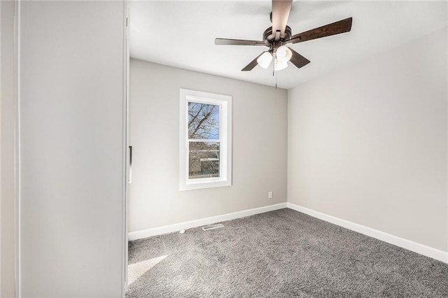 carpeted spare room with a ceiling fan and baseboards