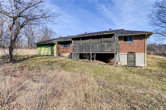 rear view of property with brick siding, a chimney, a yard, and a sunroom