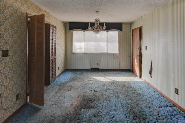 unfurnished dining area with a notable chandelier, carpet, and a textured ceiling