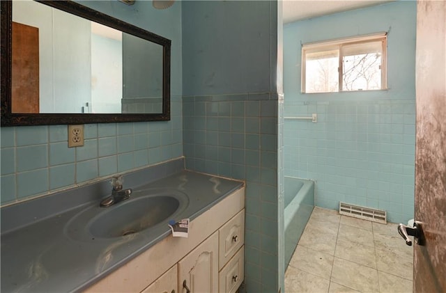 bathroom with visible vents, a tub, tile walls, tile patterned flooring, and vanity