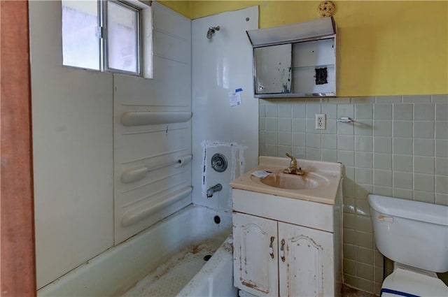 full bath with a wainscoted wall, toilet, tile walls, bathtub / shower combination, and vanity