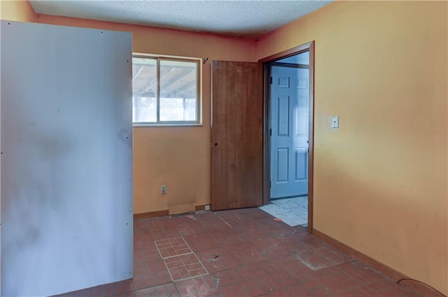 spare room featuring baseboards and a textured ceiling