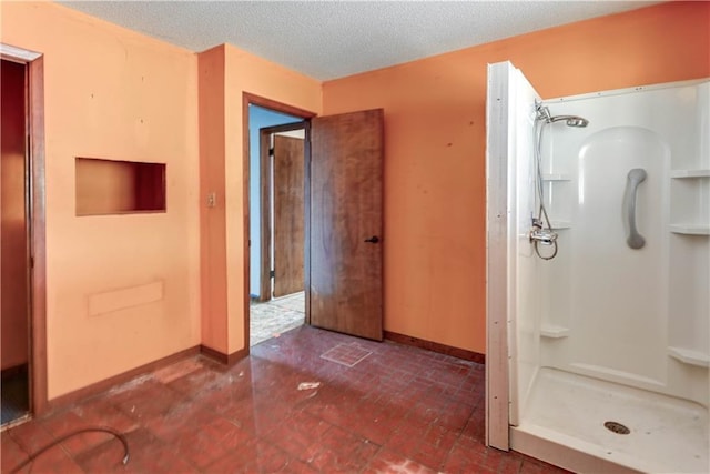 bathroom featuring a stall shower, a textured ceiling, brick floor, and baseboards