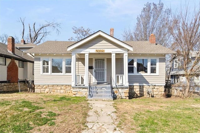 bungalow-style home featuring a front lawn and roof with shingles