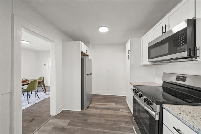 kitchen featuring stainless steel appliances, tasteful backsplash, dark wood-type flooring, and white cabinetry