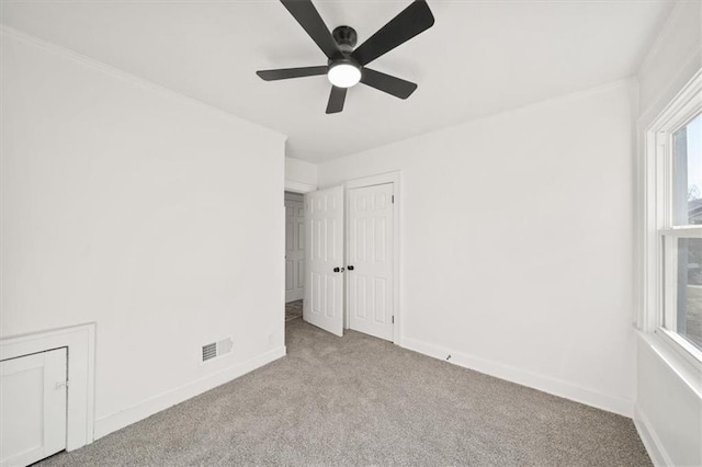 unfurnished room with visible vents, carpet floors, baseboards, and ceiling fan