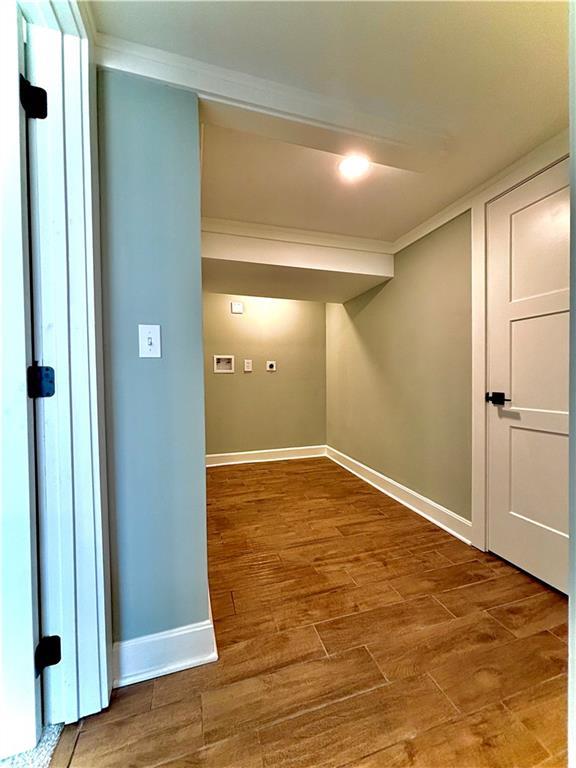 basement with ornamental molding, baseboards, and wood finished floors