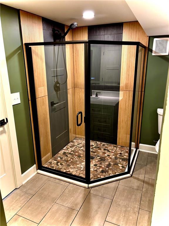 full bath featuring tile patterned floors, baseboards, toilet, and a shower stall