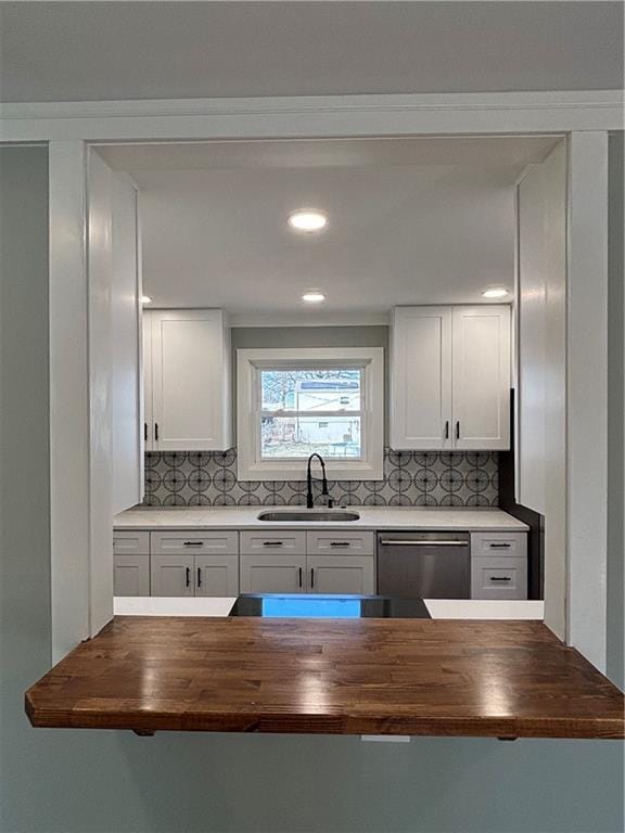 kitchen with white cabinets, stainless steel dishwasher, wood counters, and a sink