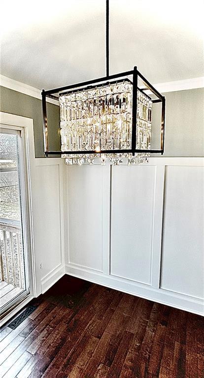 details featuring a decorative wall, crown molding, and wood finished floors