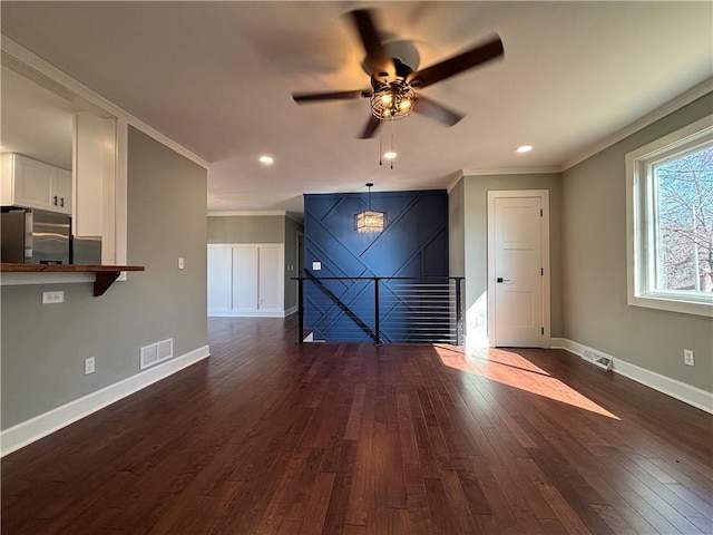 unfurnished living room with dark wood-type flooring, crown molding, visible vents, and baseboards