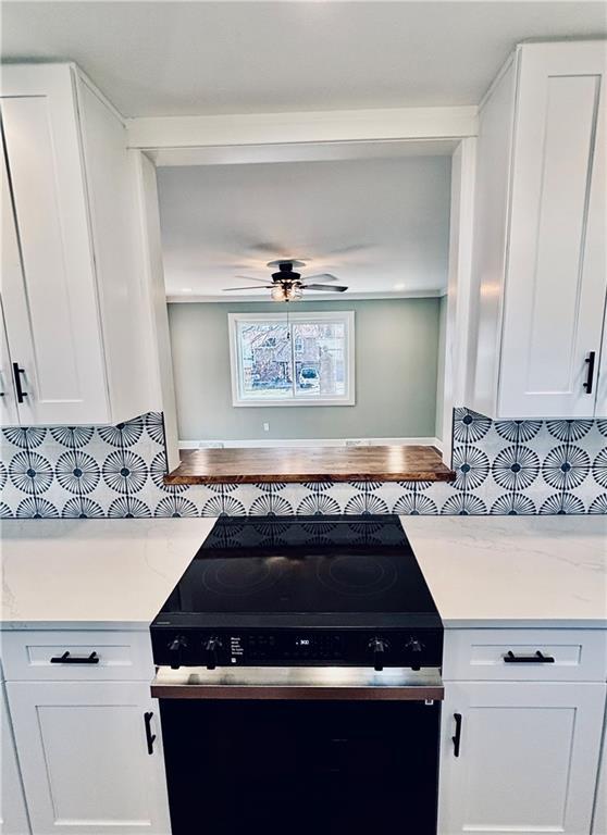 kitchen with electric range, white cabinets, decorative backsplash, light stone countertops, and ceiling fan