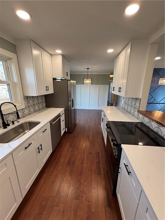 kitchen with a sink, dark wood-type flooring, appliances with stainless steel finishes, and white cabinetry