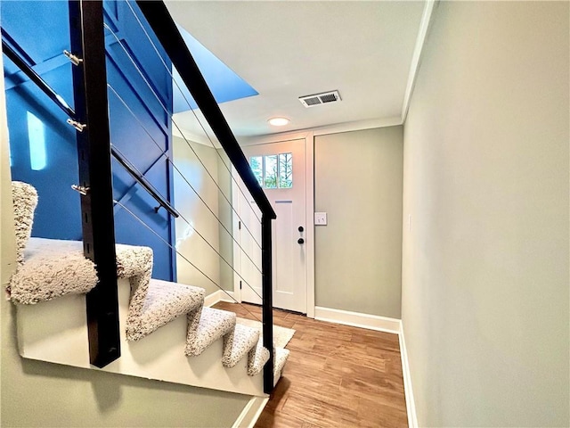 stairway with visible vents, ornamental molding, baseboards, and wood finished floors