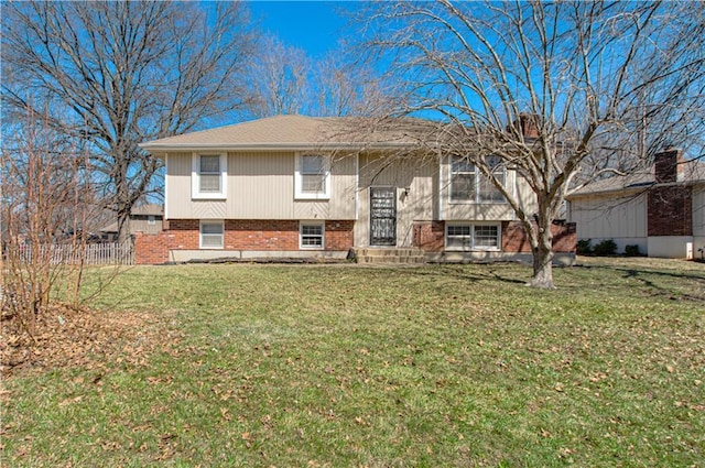 view of front of home featuring brick siding, a front lawn, and fence