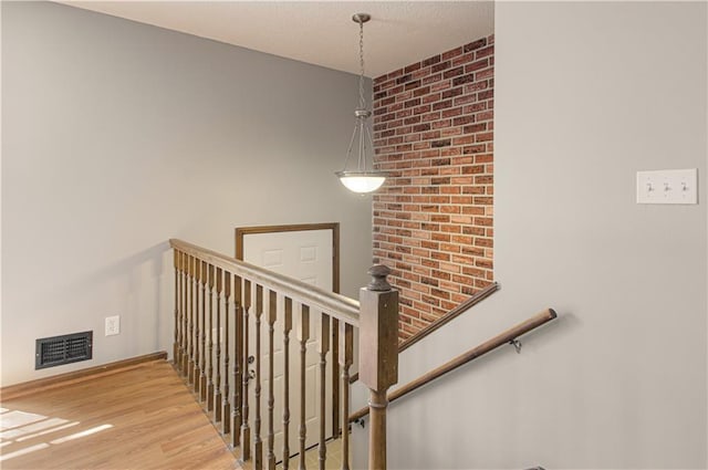 stairway featuring visible vents, baseboards, and wood finished floors