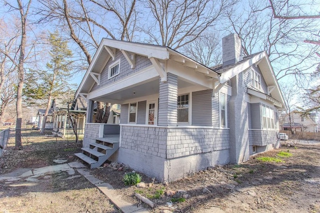 view of front of home featuring a porch, fence, and a chimney