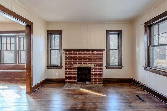 unfurnished living room with a healthy amount of sunlight, a brick fireplace, and hardwood / wood-style floors