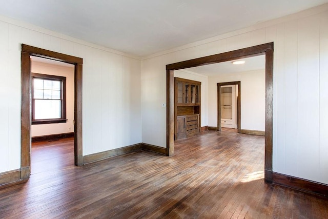 spare room featuring dark wood-style floors and baseboards