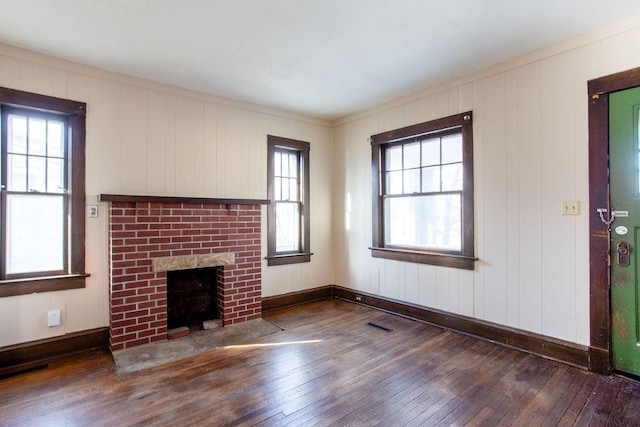 unfurnished living room with baseboards, wood-type flooring, visible vents, and a fireplace