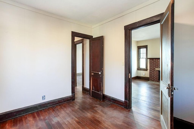 spare room with dark wood finished floors, crown molding, and baseboards