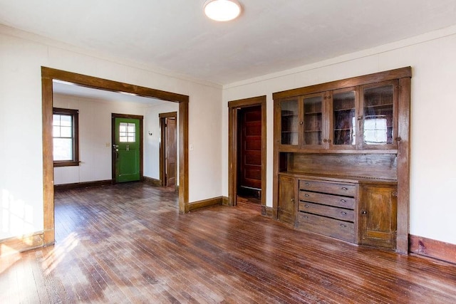 unfurnished living room with baseboards, wood-type flooring, and ornamental molding