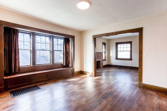 spare room featuring hardwood / wood-style flooring, a fireplace, visible vents, and baseboards