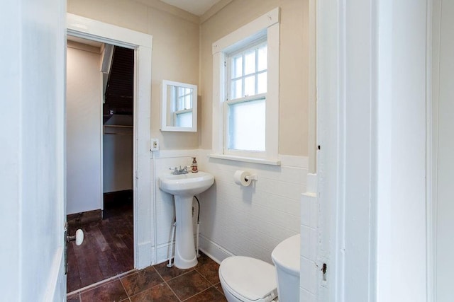 bathroom featuring a wainscoted wall, a sink, tile patterned flooring, tile walls, and toilet