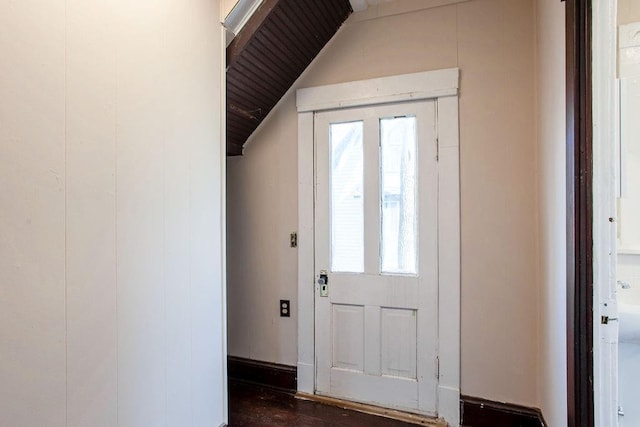 foyer entrance with a wealth of natural light, dark wood-type flooring, and vaulted ceiling