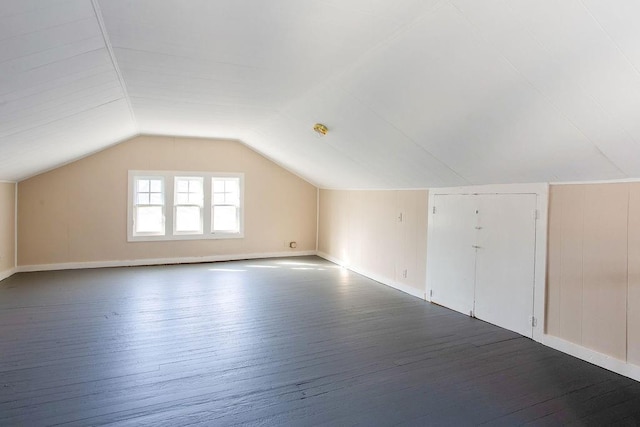 additional living space featuring dark wood-type flooring and lofted ceiling