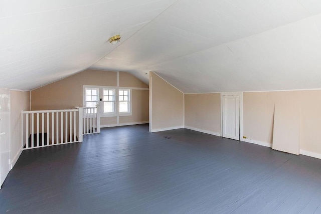 additional living space featuring dark wood-type flooring, baseboards, and vaulted ceiling