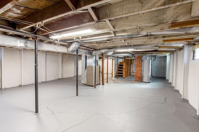 unfinished basement featuring gas water heater, stairway, and heating unit