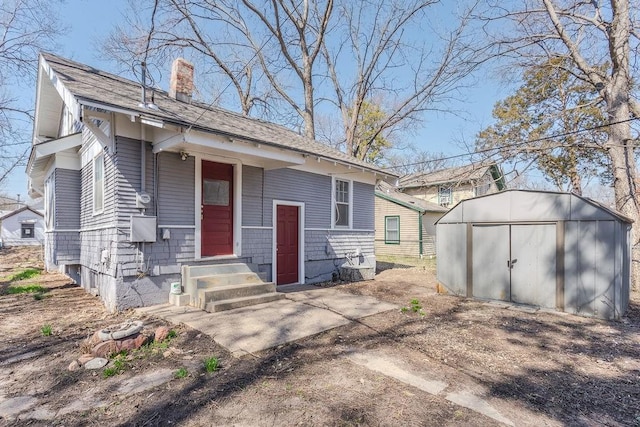 rear view of property with an outbuilding, a shed, and a chimney