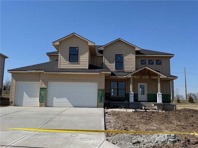 view of front facade with concrete driveway, an attached garage, board and batten siding, and a shingled roof