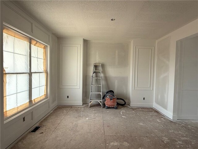 spare room with a textured ceiling, baseboards, and a healthy amount of sunlight