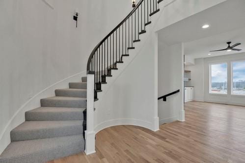 stairway featuring ceiling fan, baseboards, and wood finished floors