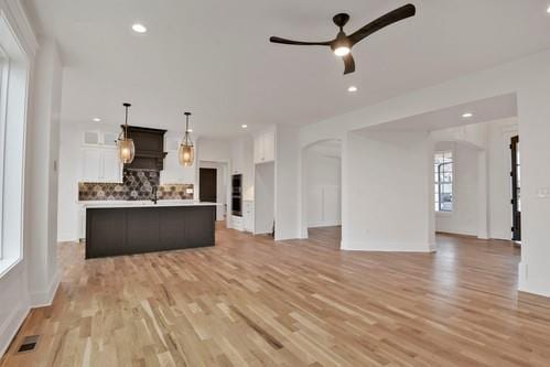 unfurnished living room with recessed lighting, light wood finished floors, baseboards, and ceiling fan